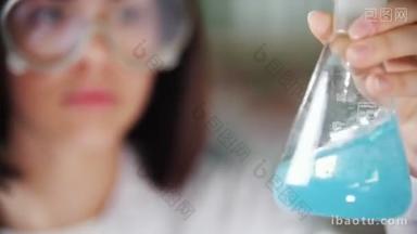 化学实验室里的年轻女子拿着烧瓶液, 摇着摇着。把注意力集中在烧瓶上.